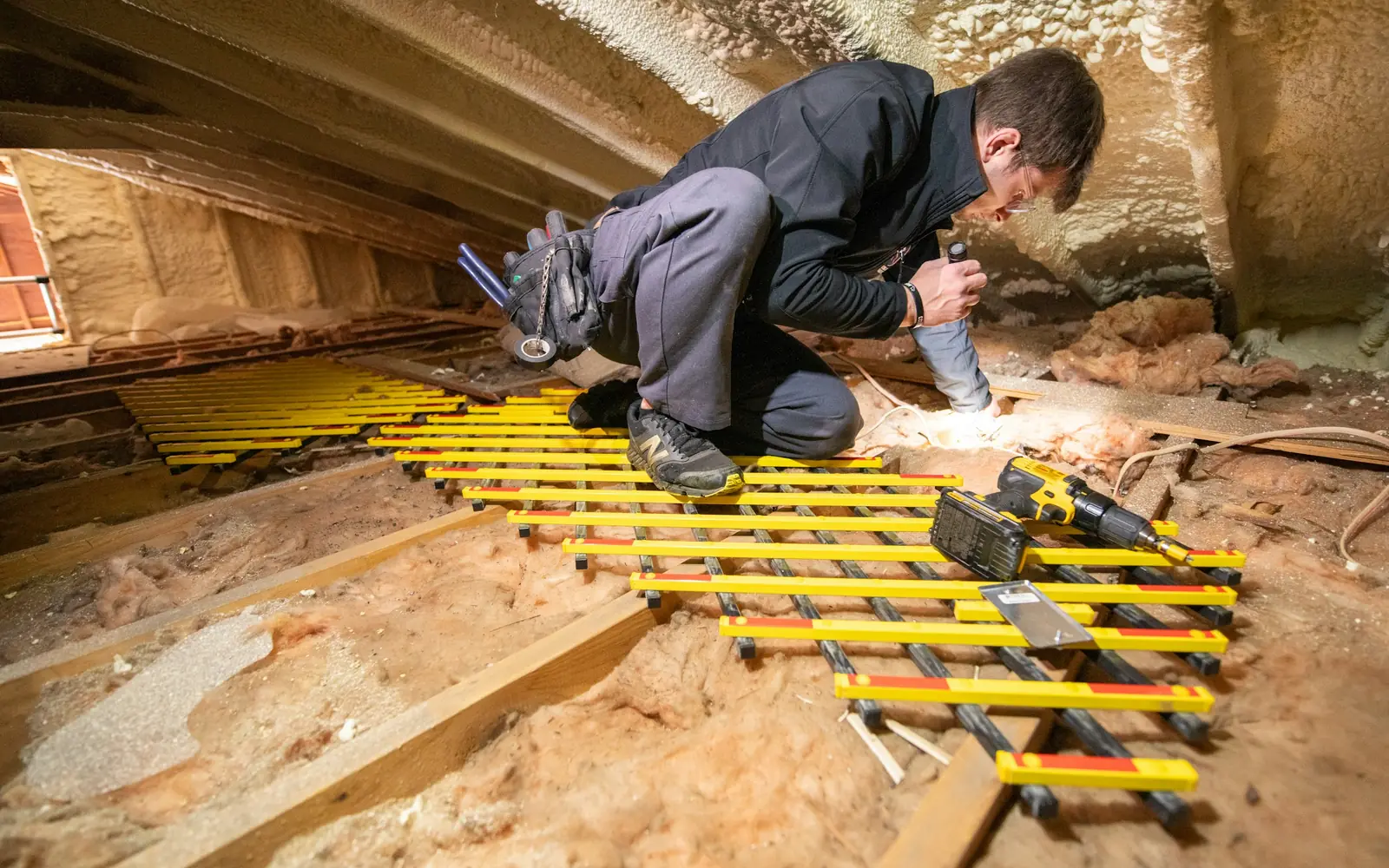 Handwerker verlegt Laufstege auf der gedämmten obersten Geschossdecke